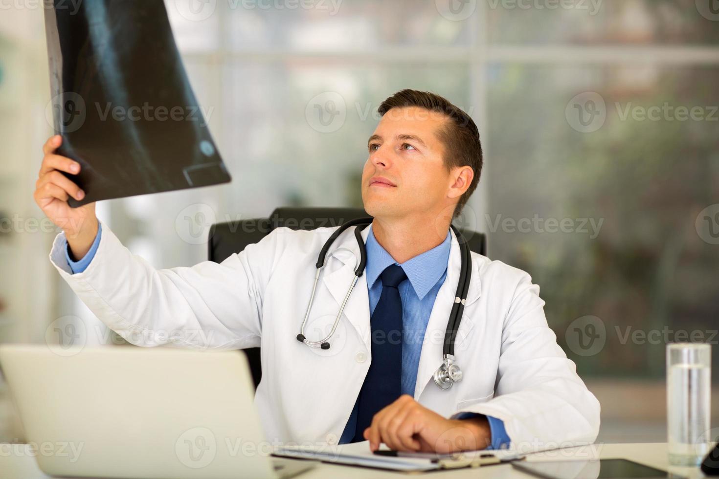 Doctor mirando la radiografía del paciente en el consultorio foto