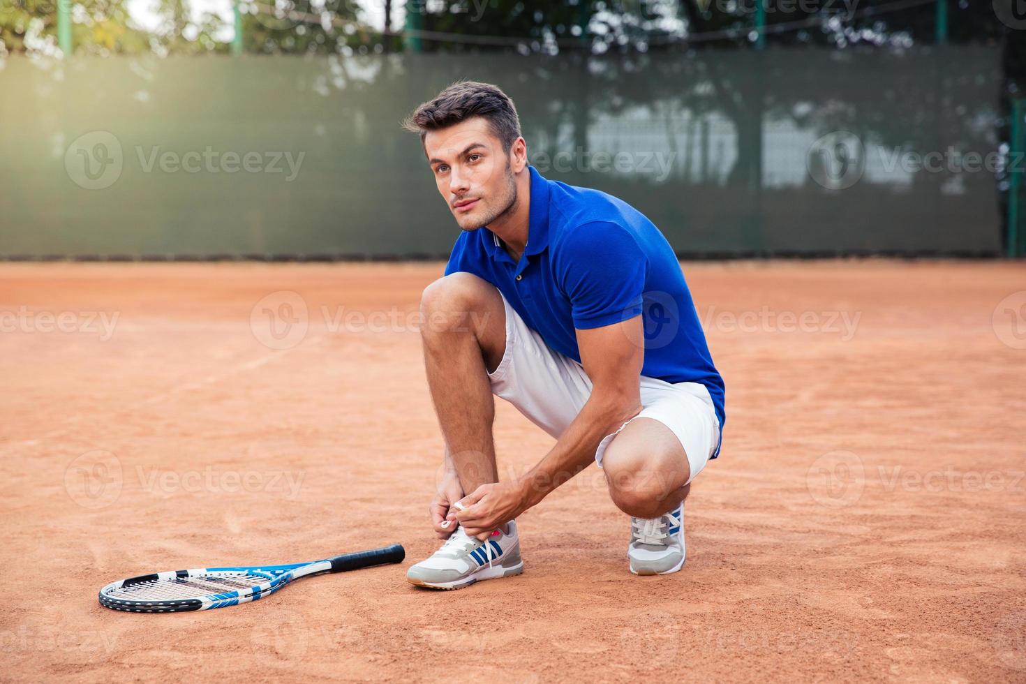 Male tennis player tying shoelaces 963551 Stock Photo at Vecteezy