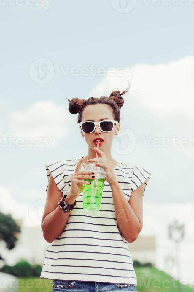 Funky woman drinking water against the sky photo