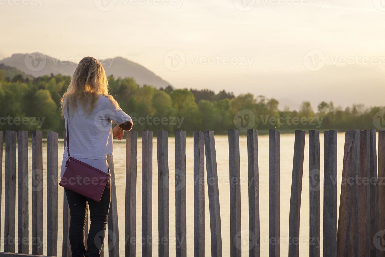 mujer mirando el atardecer en el lago foto