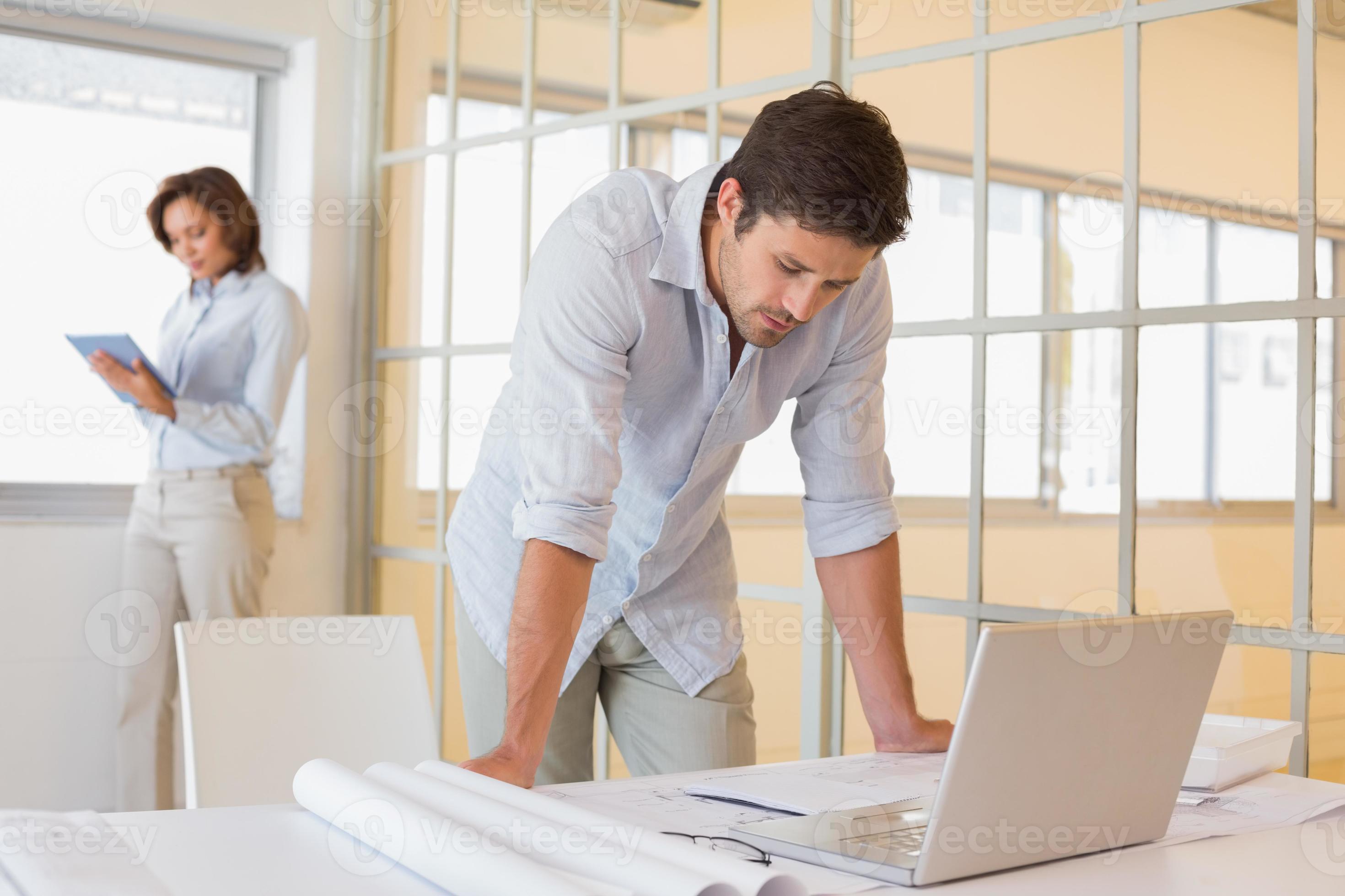 Businessman using laptop with colleague in background photo