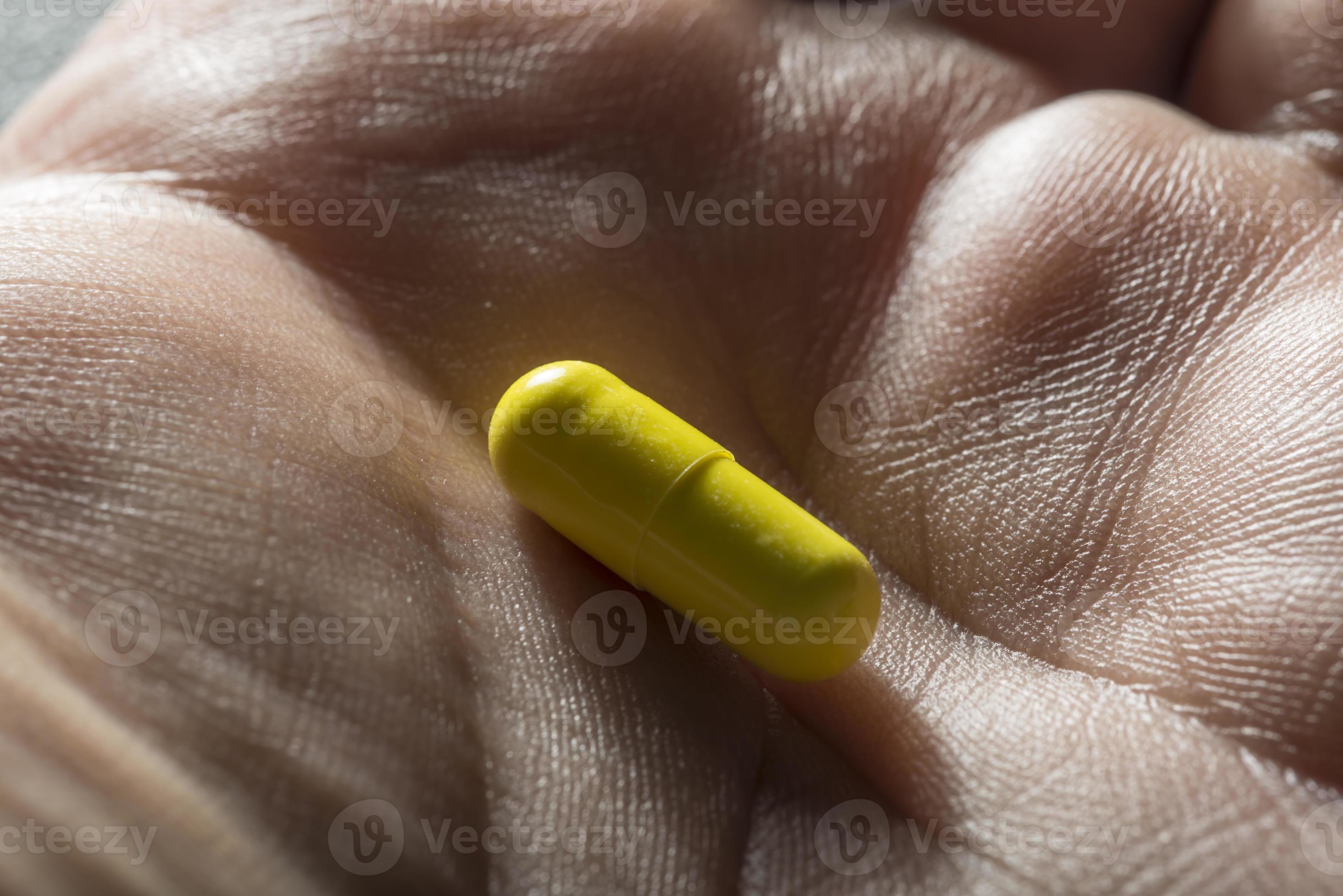 Bare Hand Holding One Yellow Medicinal Tablet Stock Photo