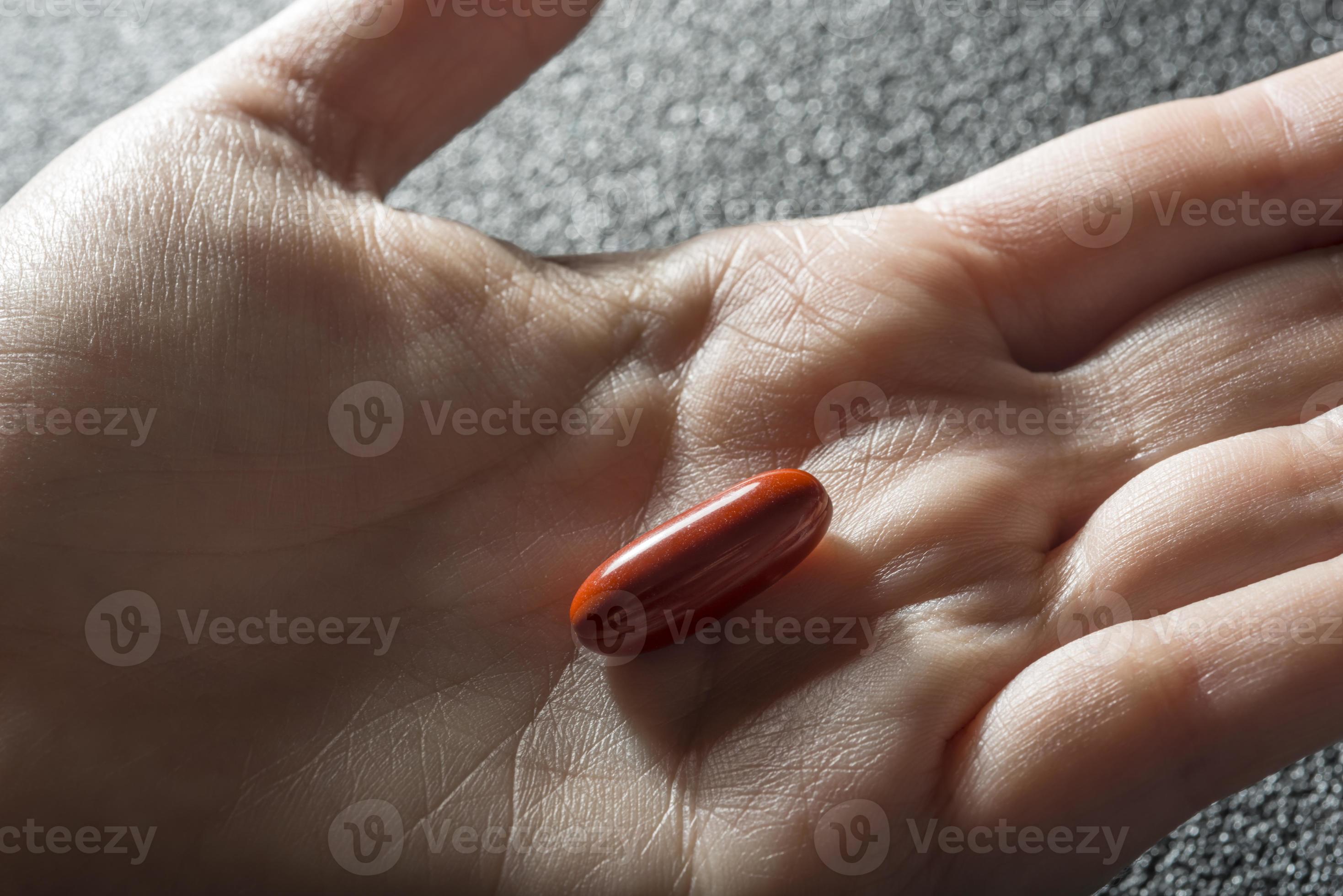 Bare Hand Holding One Red Medicinal Tablet Stock Photo