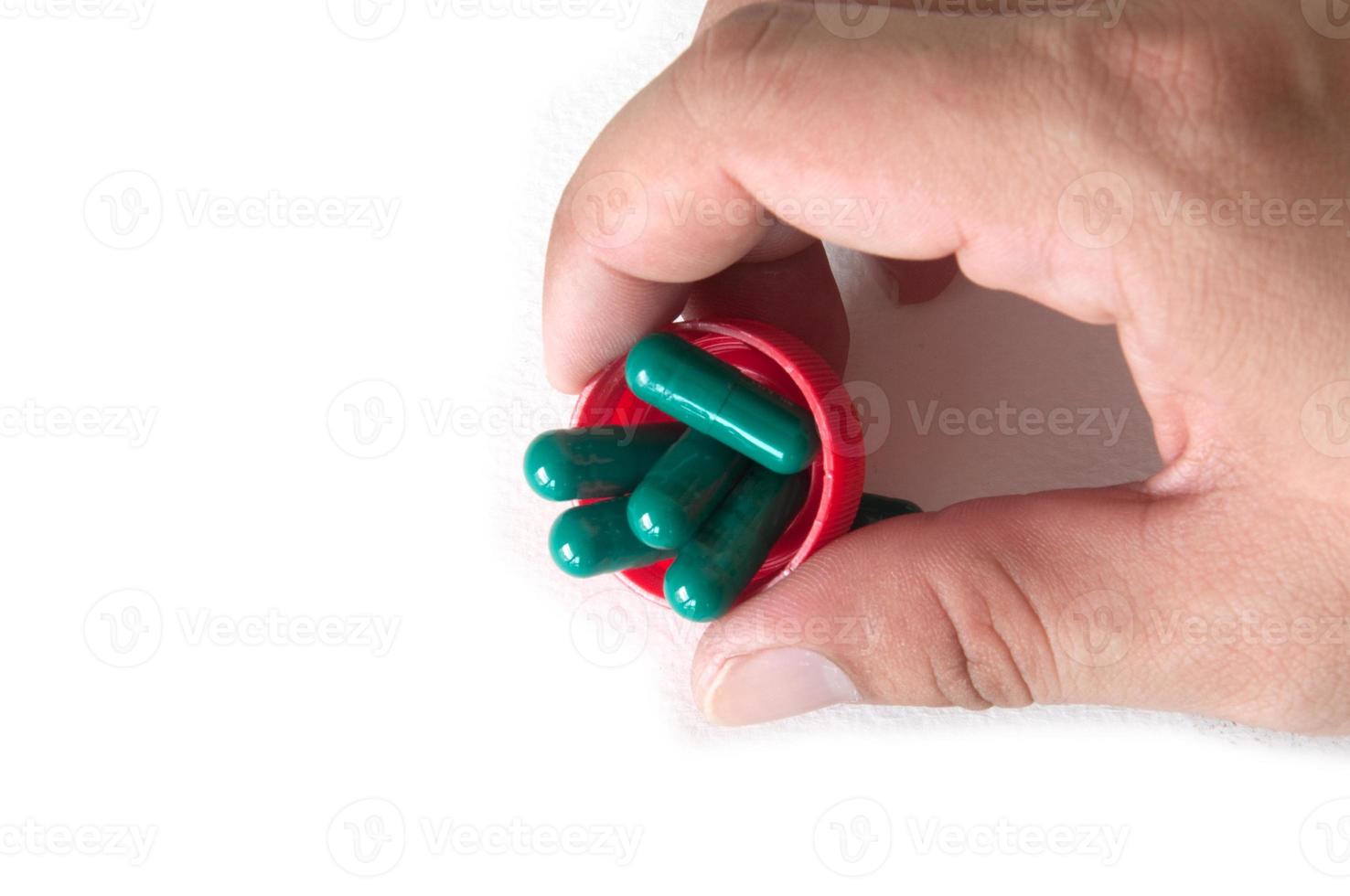 green medical capsule in a hand, isolated photo
