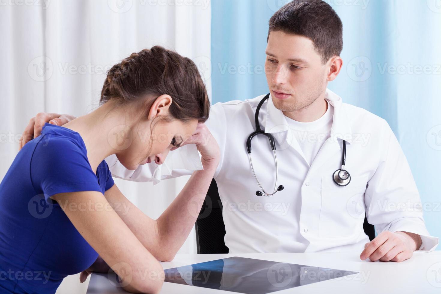 el joven doctor consolando a una mujer triste foto