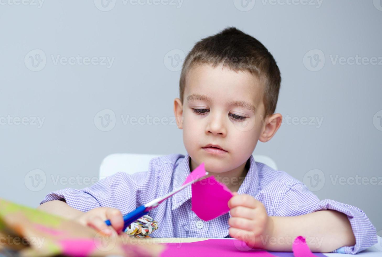 Boy is cutting paper using scissors photo