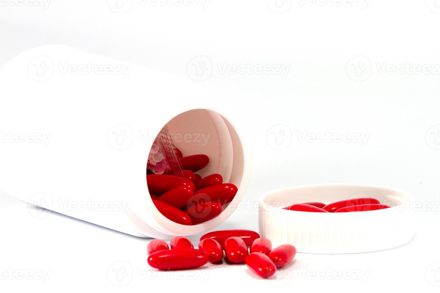 medicina pastillas rojas saliendo de la botella blanca foto