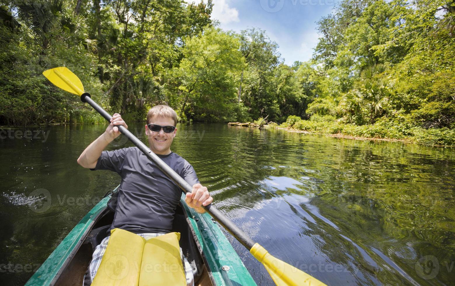 hombre feliz en kayak por el hermoso río de la jungla foto