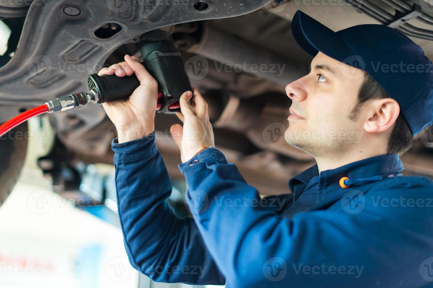 Mecánico cambiando la rueda del coche en el taller de reparación de automóviles foto