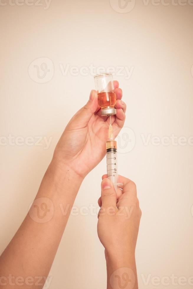 Syringe with vial on hands of a nurse photo
