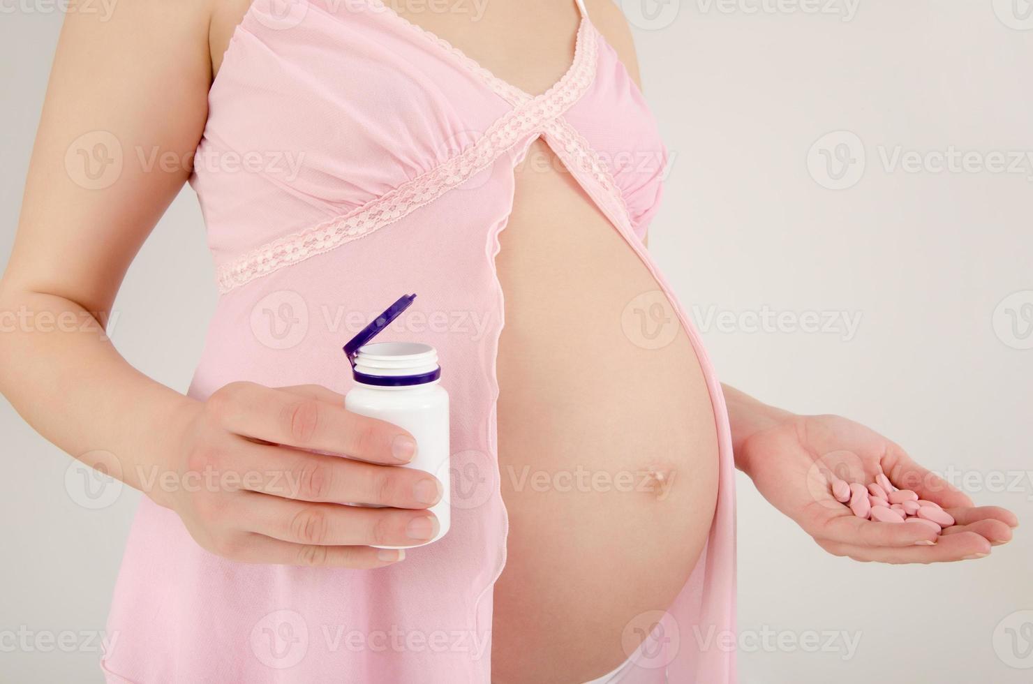 Woman expecting a baby holding pills in her hands. photo