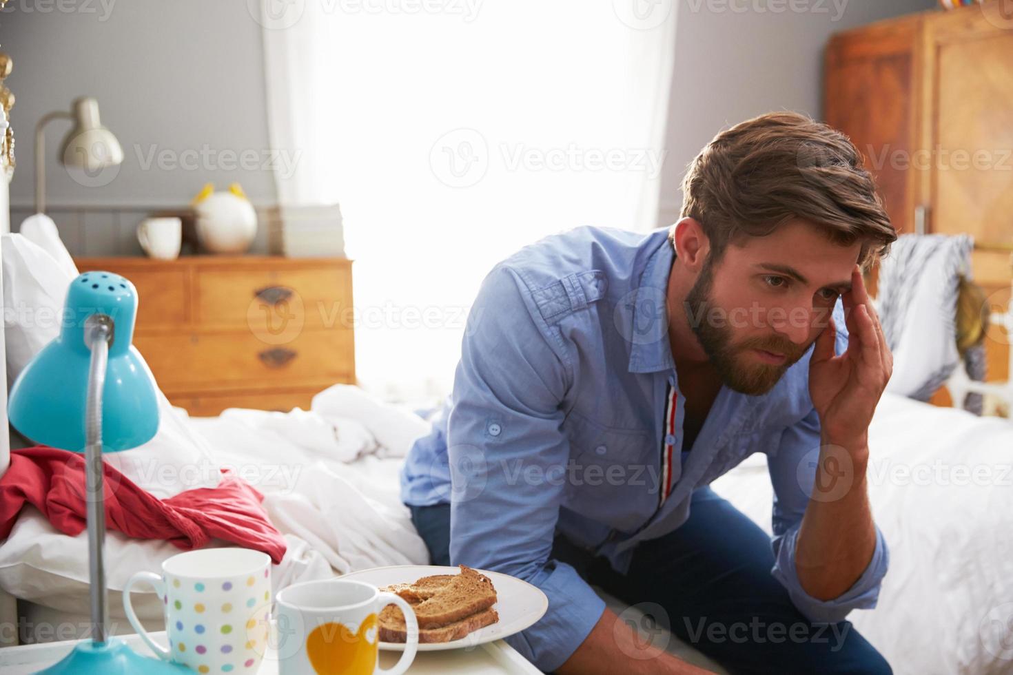 hombre que sufre de depresión sentado en el borde de la cama foto