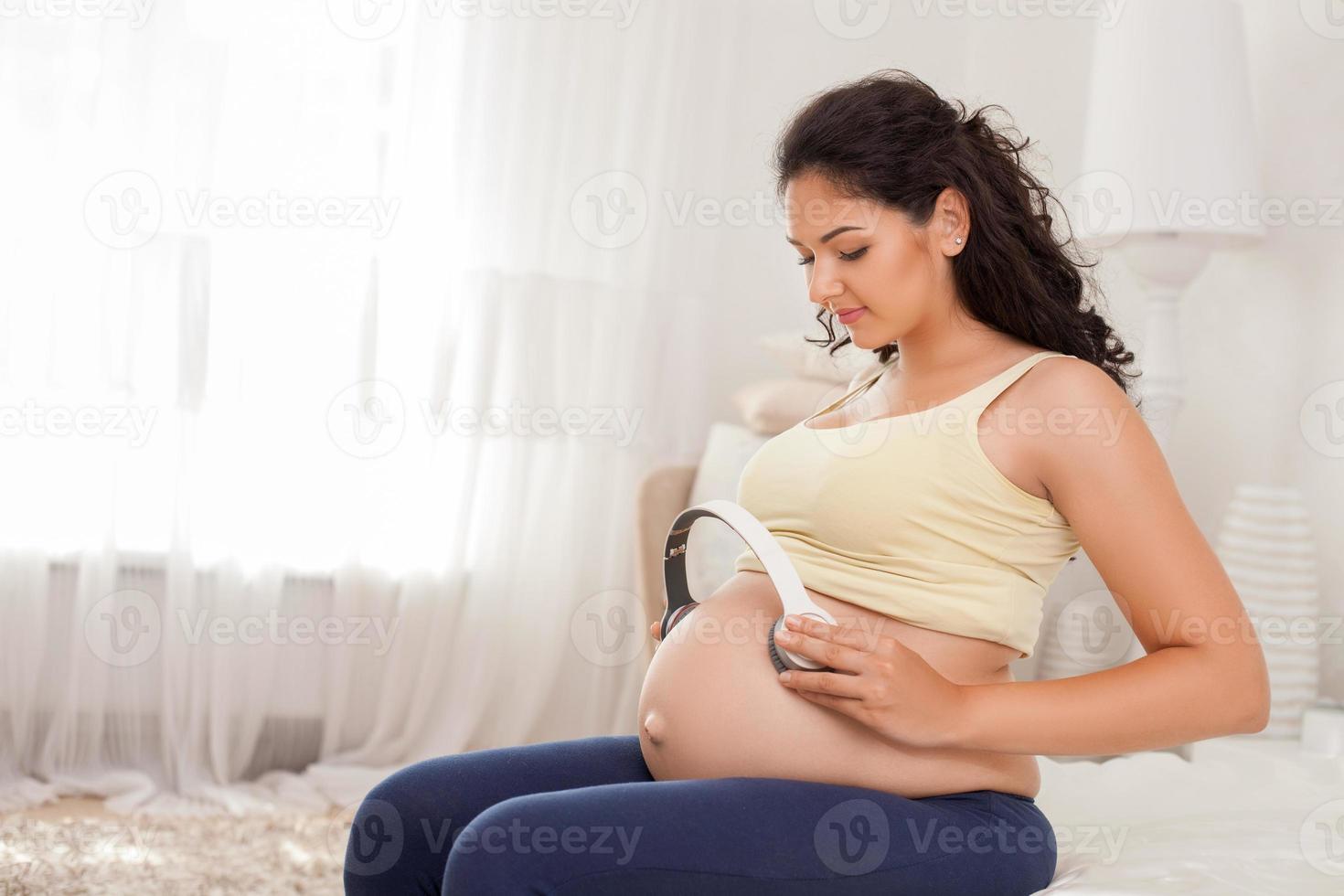 Cheerful expectant mother is getting in touch with her child photo