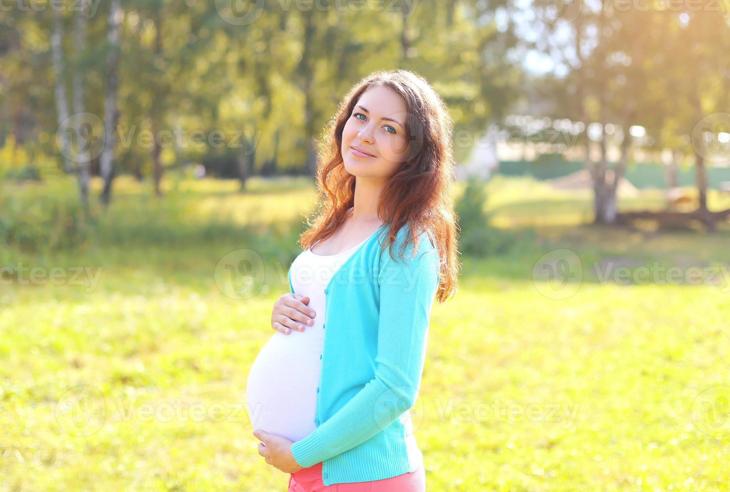 Download Pretty smiling pregnant woman in sunny summer day for free.