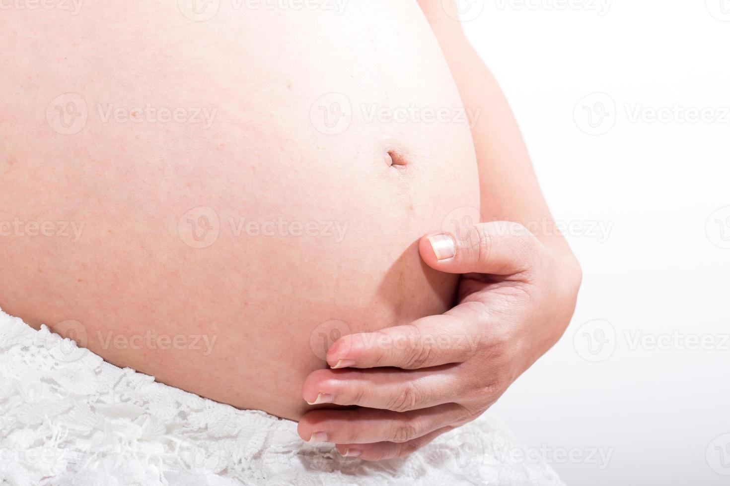 Mujer embarazada acariciando su vientre sobre fondo blanco. foto
