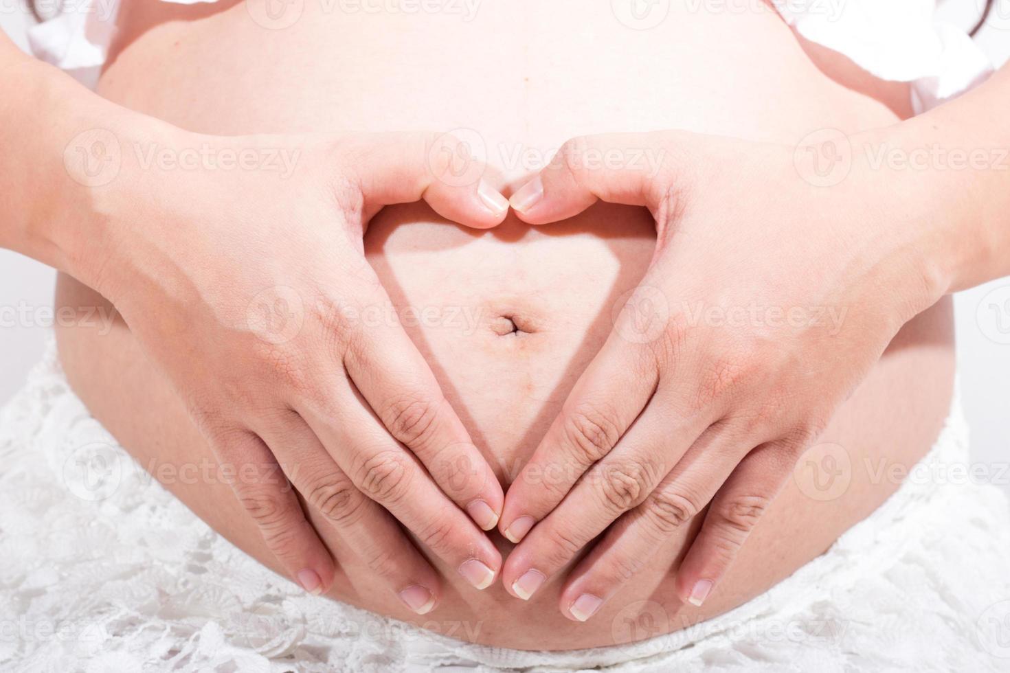 Mujer embarazada acariciando su vientre sobre fondo blanco. foto