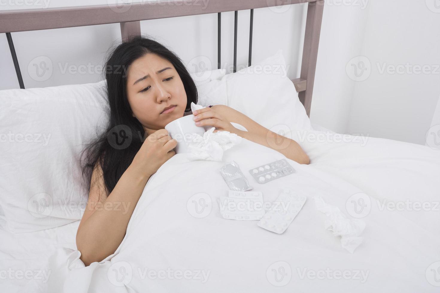 mujer que sufre de frío tomando un café en la cama foto