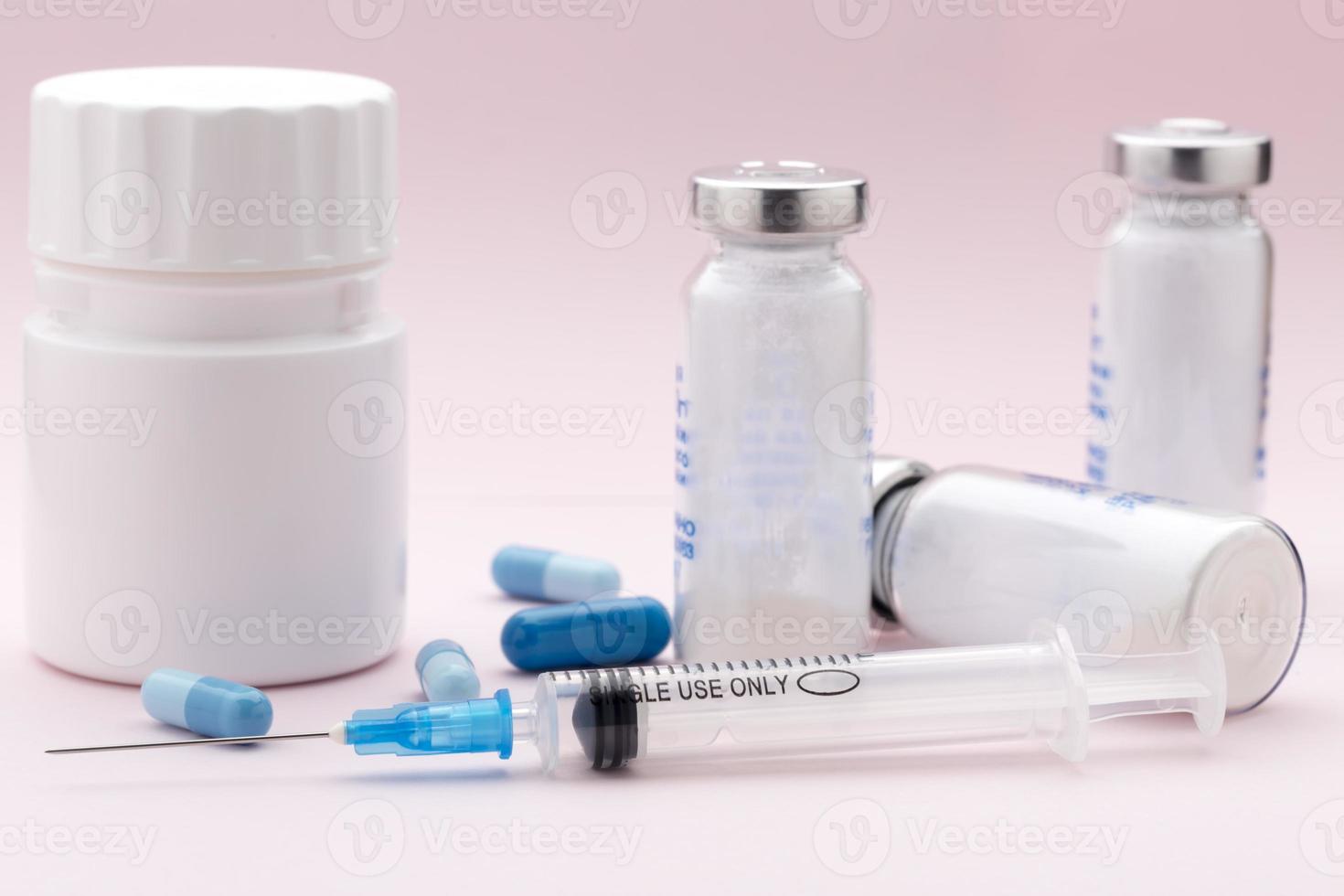 El conjunto de frascos de medicamentos, píldoras azules y jeringa de inyección foto