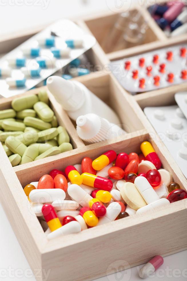Píldoras médicas y ampollas en caja de madera. foto