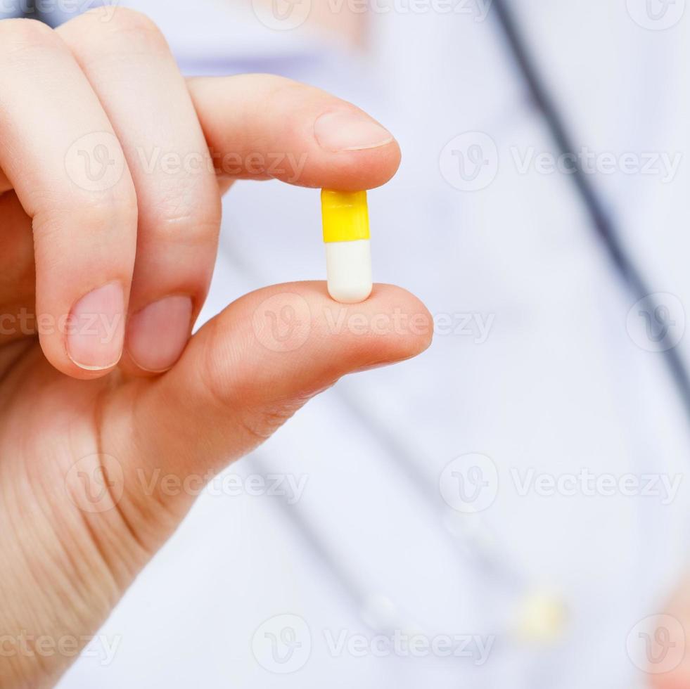 la enfermera sostiene la pastilla en los dedos foto