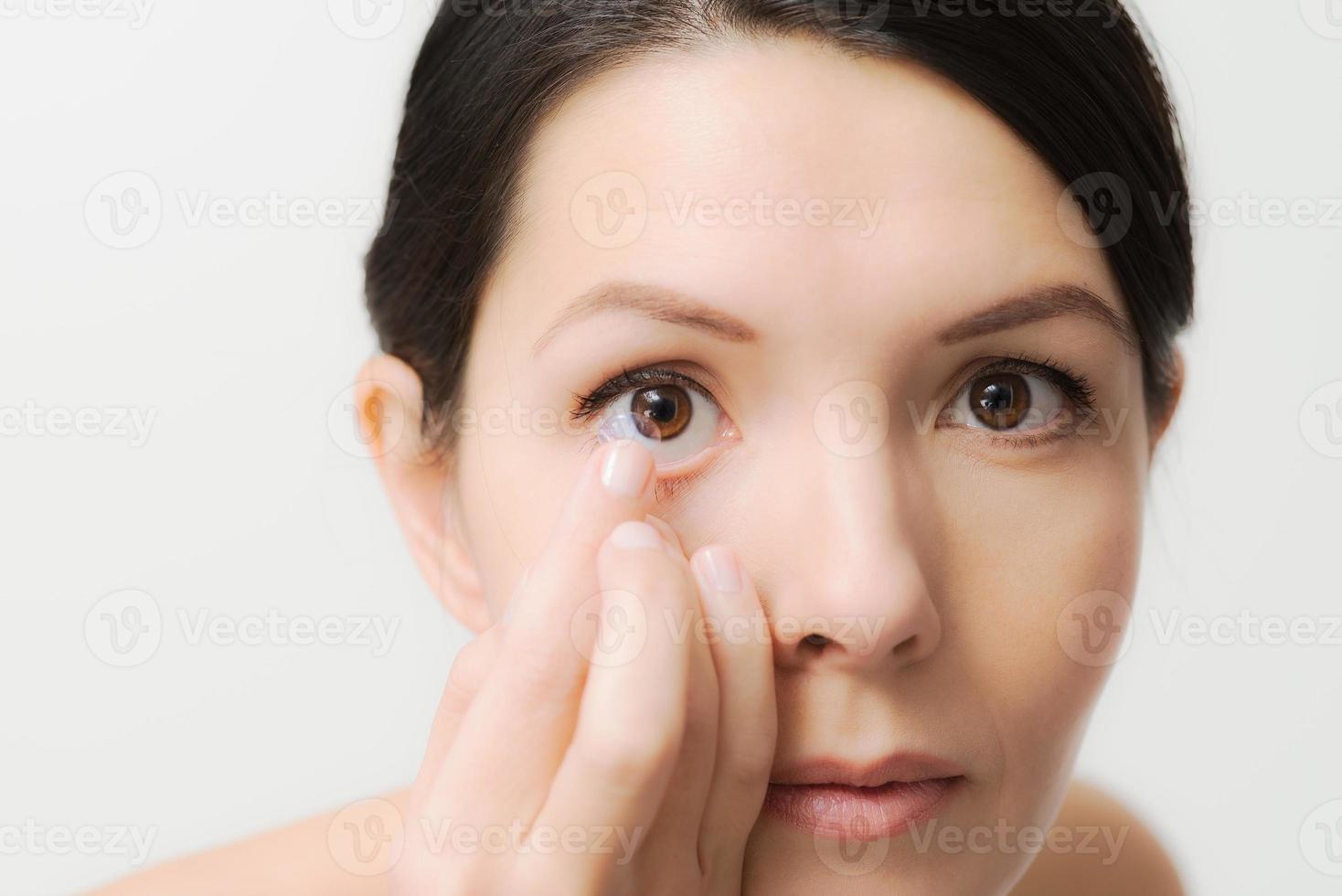 mujer a punto de colocar una lente de contacto en su ojo foto