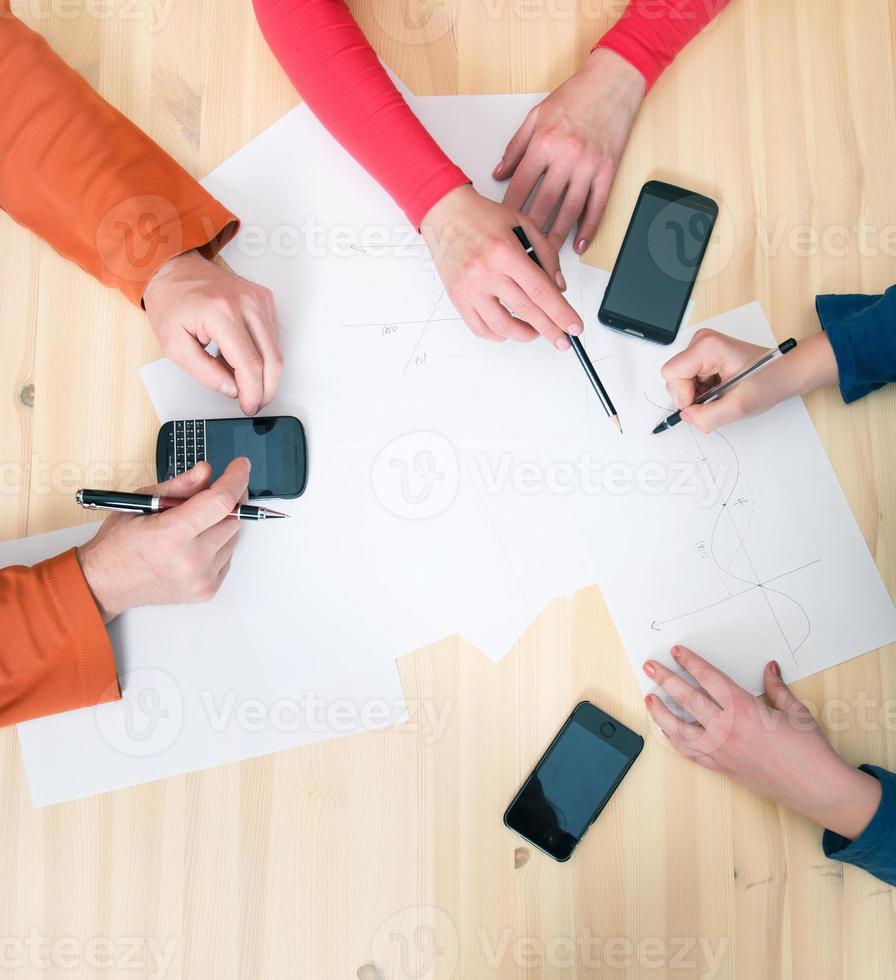 Close-up top view of businesspeople hands with pens papers smartphones. photo