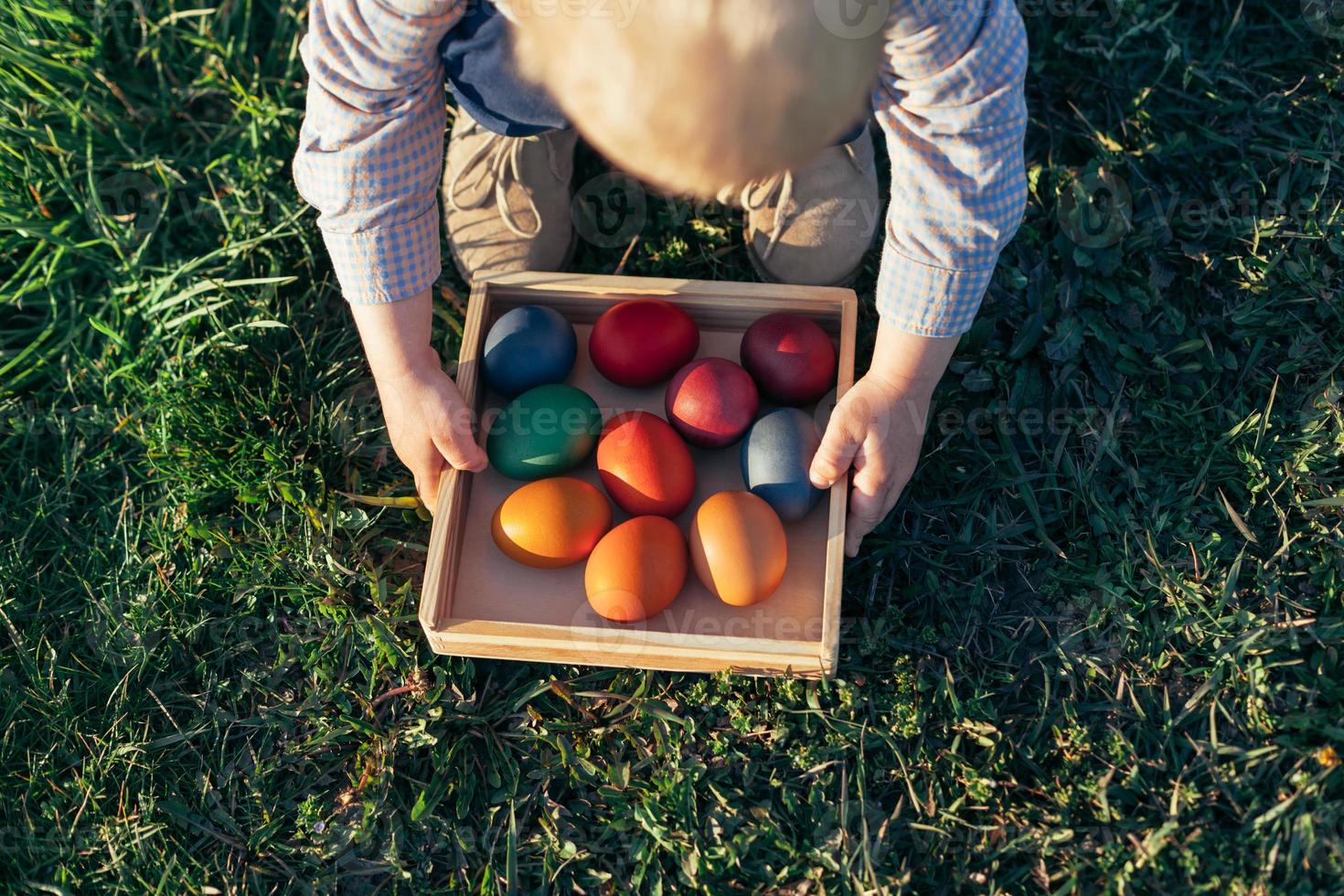 niño llevando una caja de madera con huevos de pascua al atardecer foto