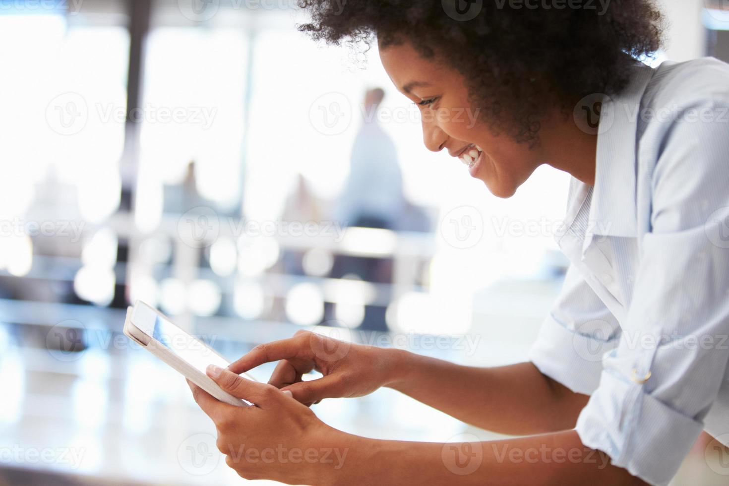 mujer joven sonriente en una oficina usando una tableta foto