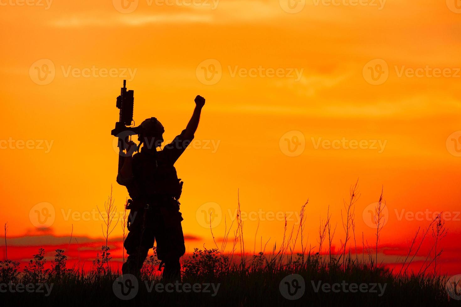 Silhouette of military soldier or officer with weapons at sunset photo