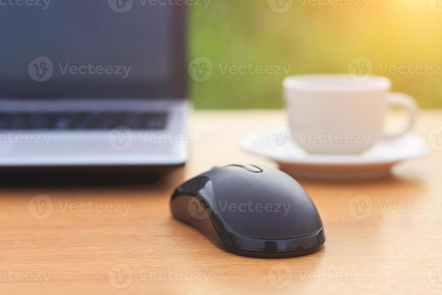 Cerrar el mouse con laptop y café en la mesa foto