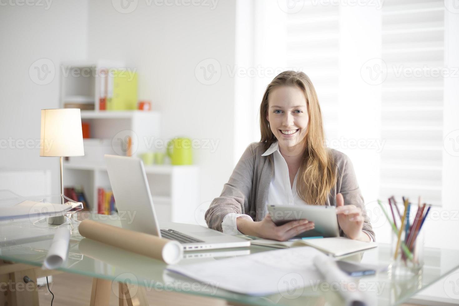 hermosa mujer joven en el lugar de trabajo usando una tableta digital foto