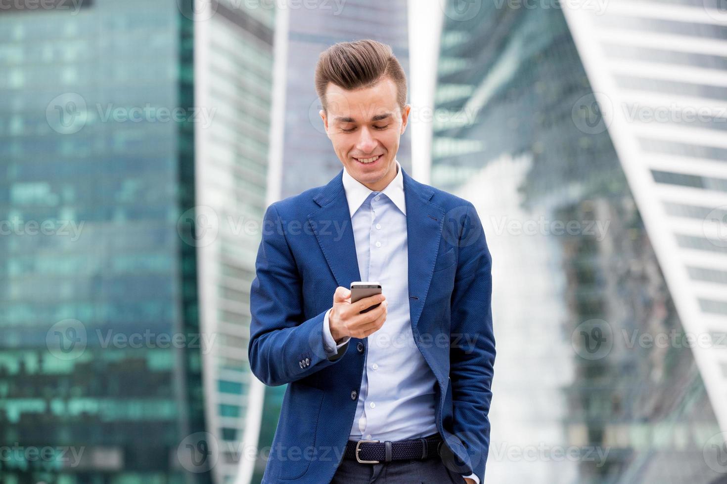 apuesto hombre de negocios en traje con teléfono inteligente en la mano foto