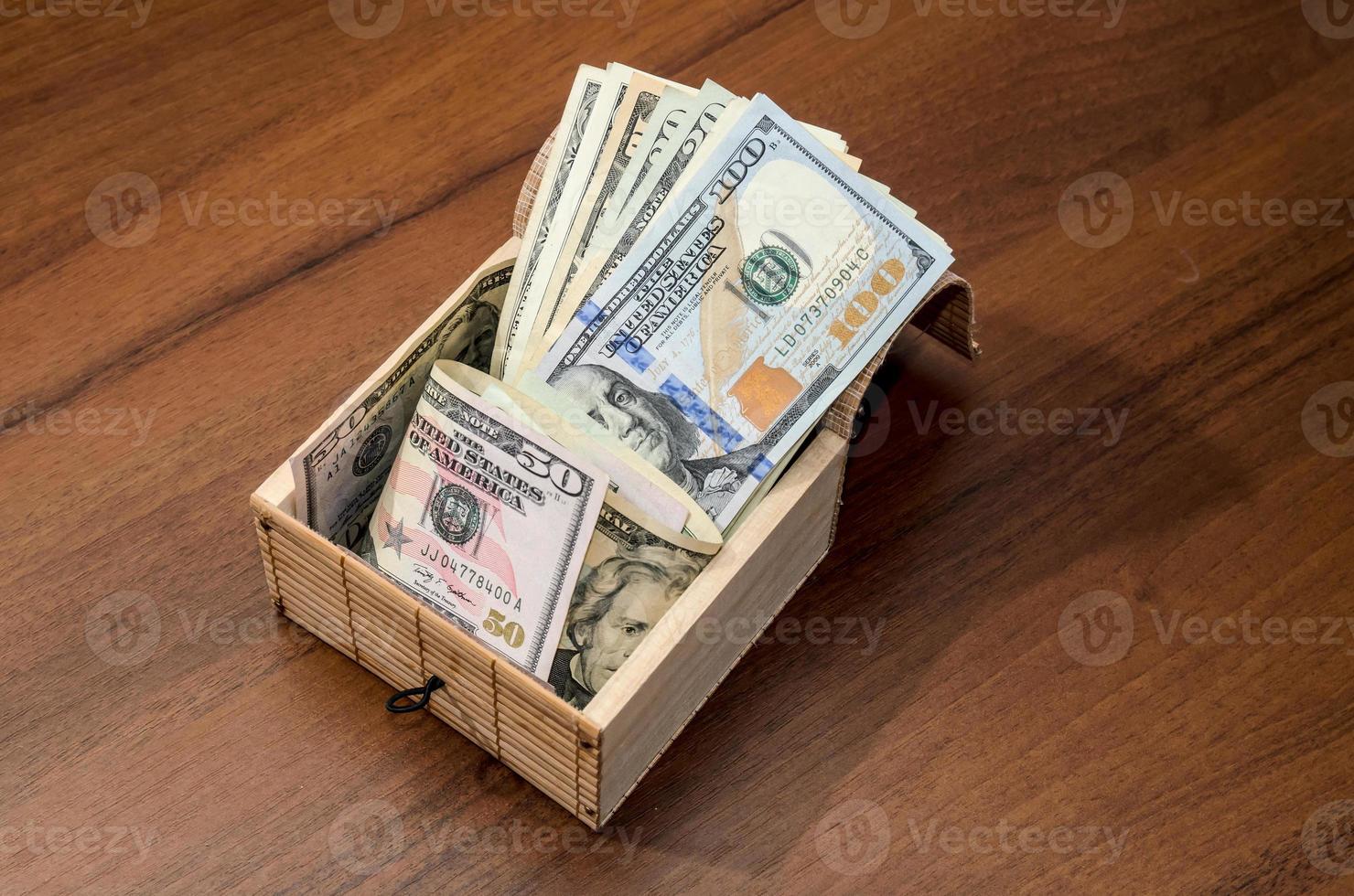 caja con billetes de un dólar sobre fondo de madera foto