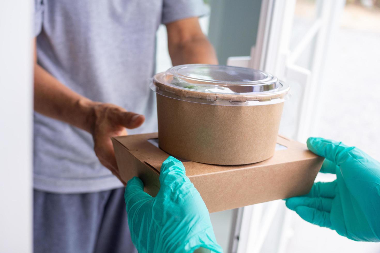 trabajador de entrega de alimentos se encuentra con el cliente en la puerta con comida para llevar foto