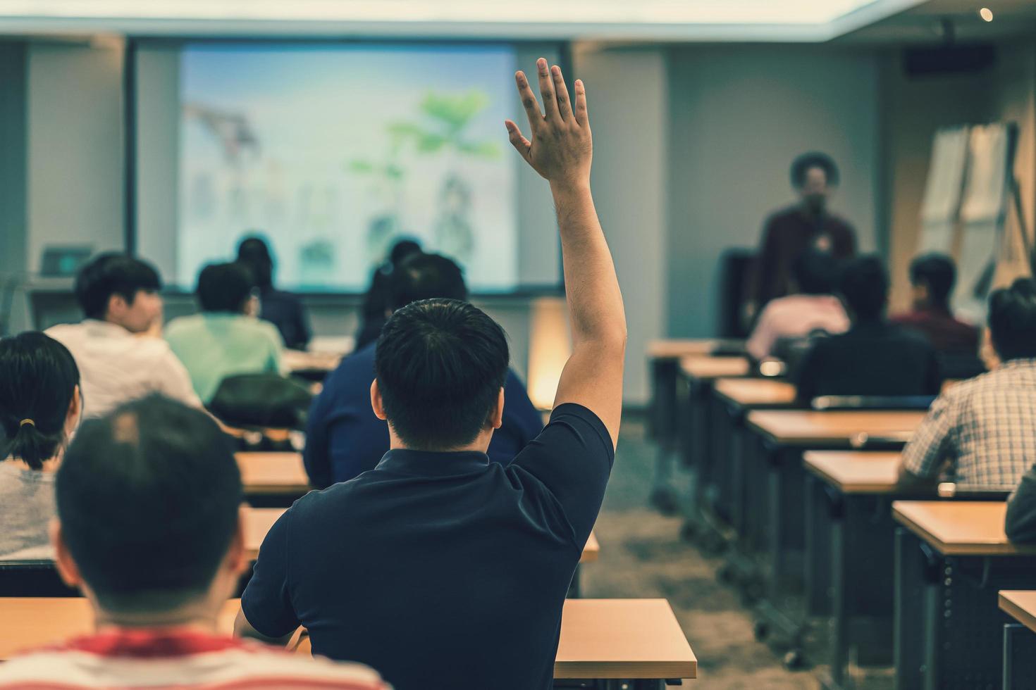 A young man raises his hand during a lecture at a workshop photo