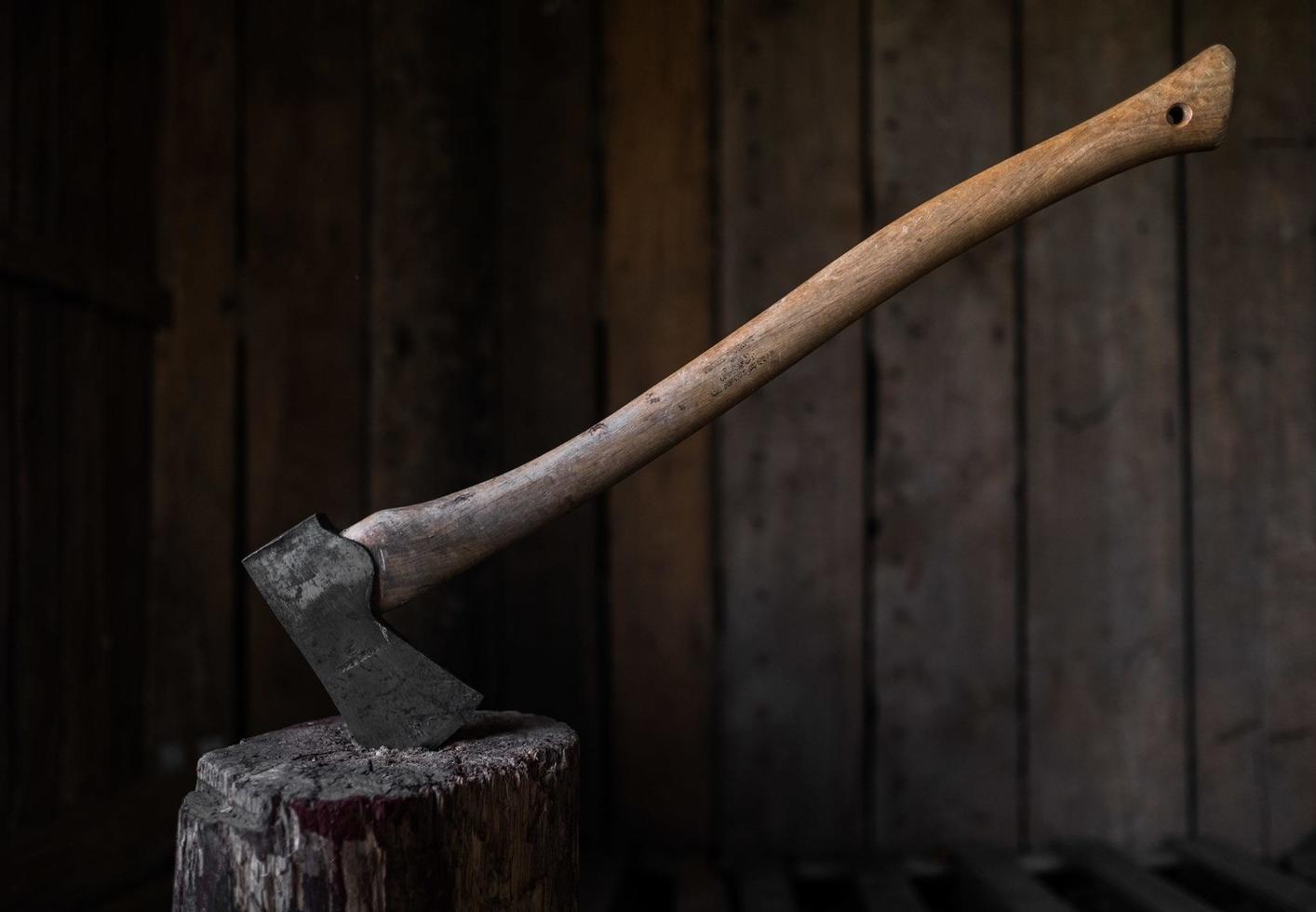 un hacha de hierro clavada en un tronco de madera foto