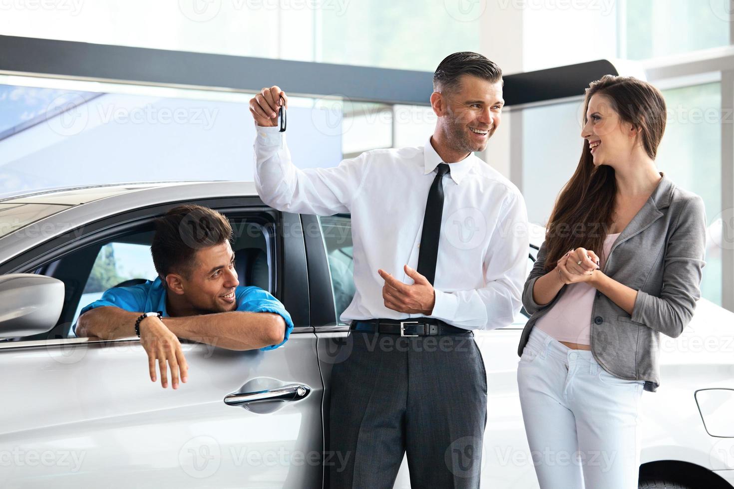 Salesman Giving Key From the New Car to Owners photo