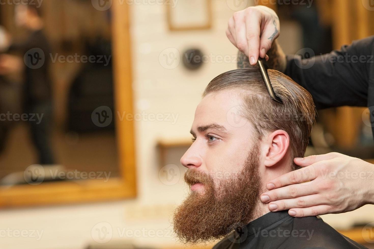 Cheerful male barber is serving his client photo