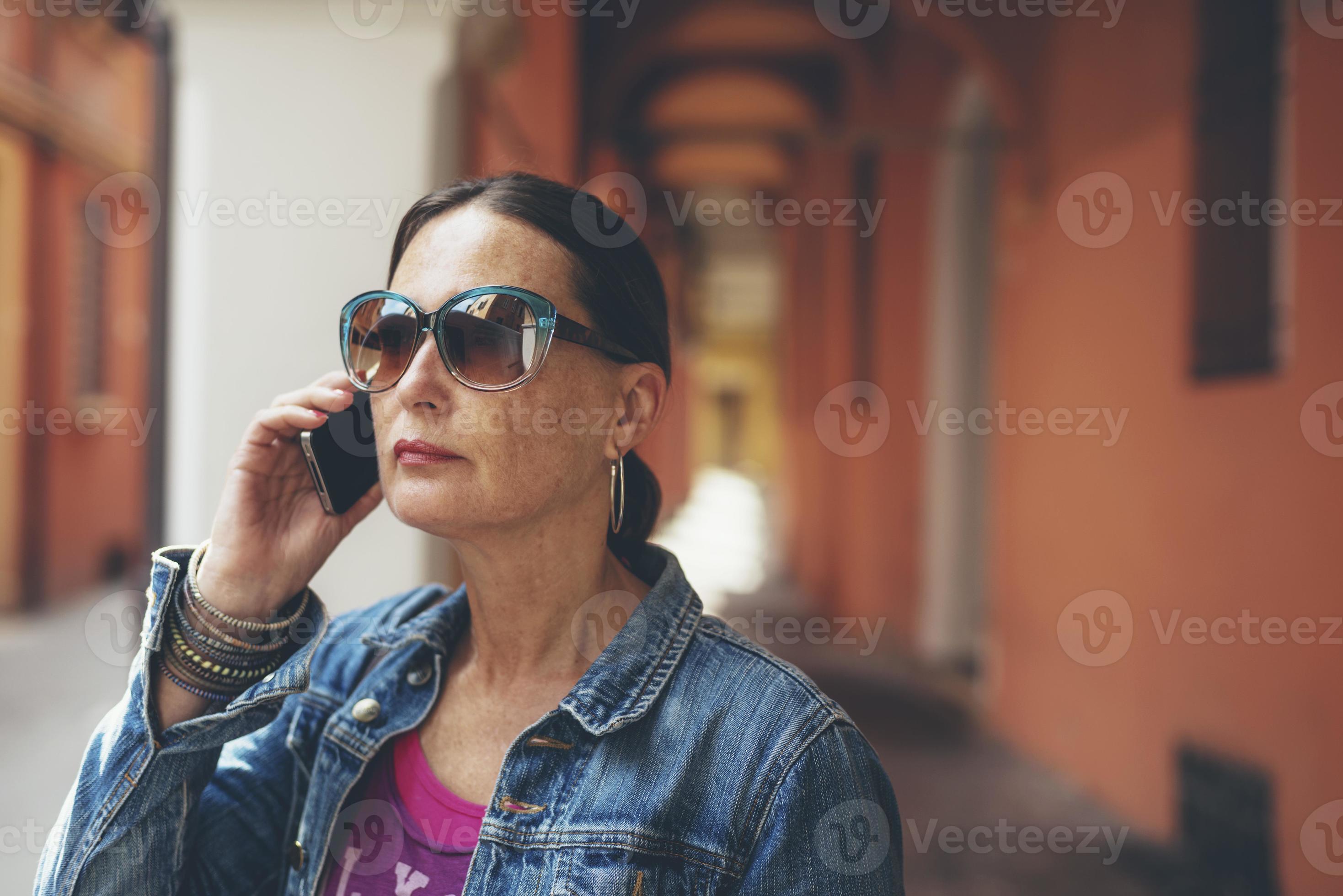 Mujer llamada con gafas de sol en las calles de Bolonia, Italia. foto