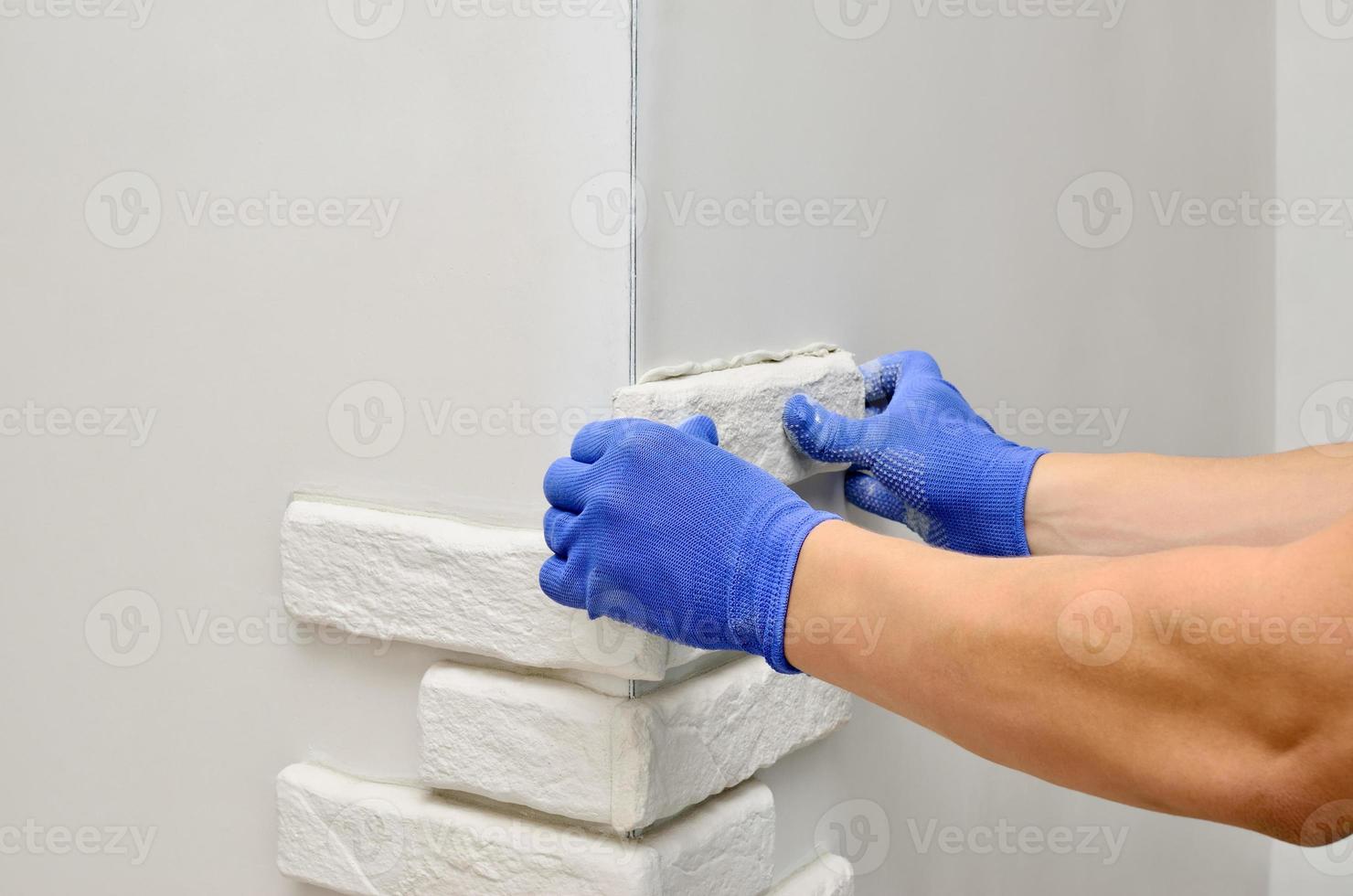 Facing wall decorative tiles, workers in blue glove photo