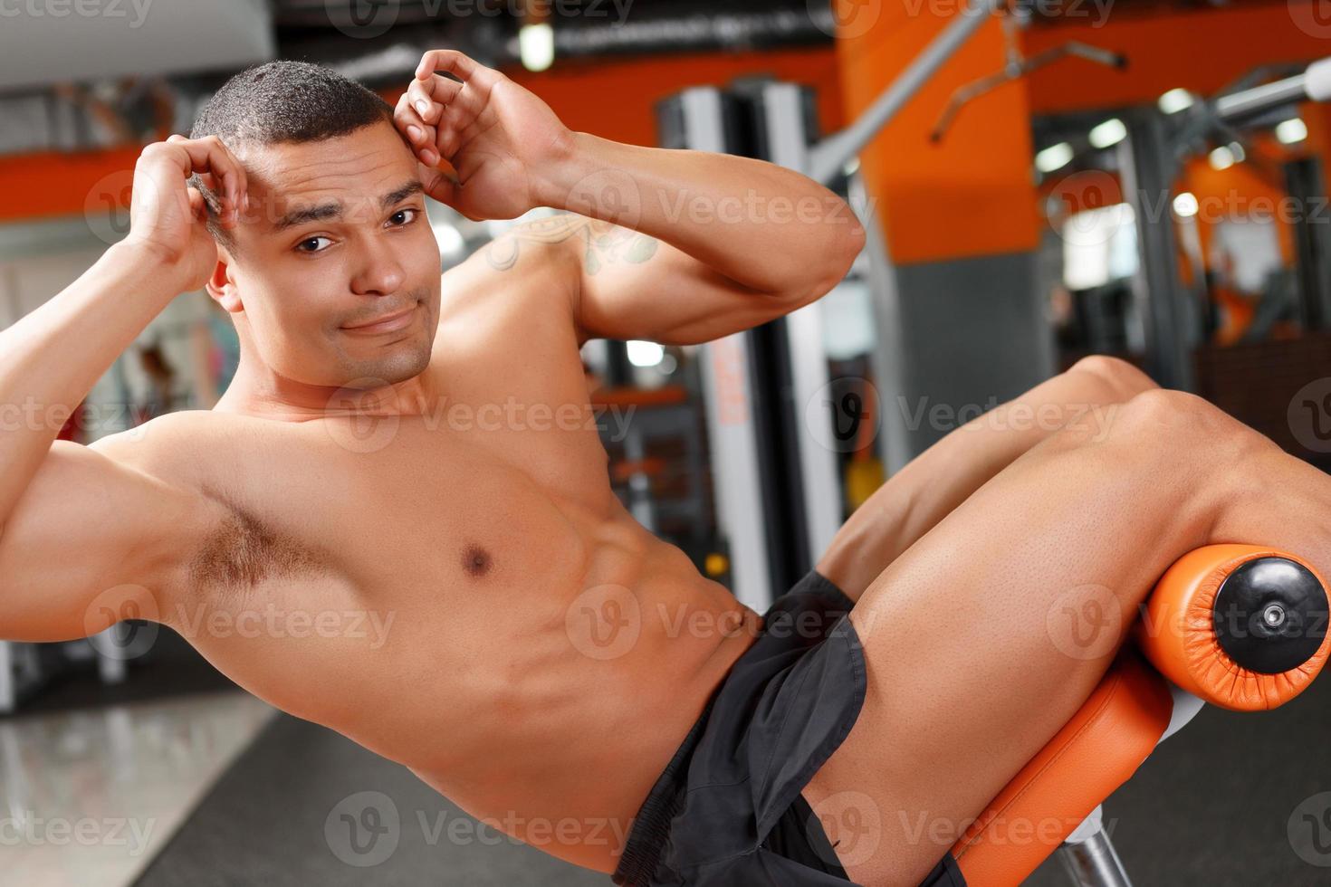 Young pleasant man doing abdominal crunches in gym photo
