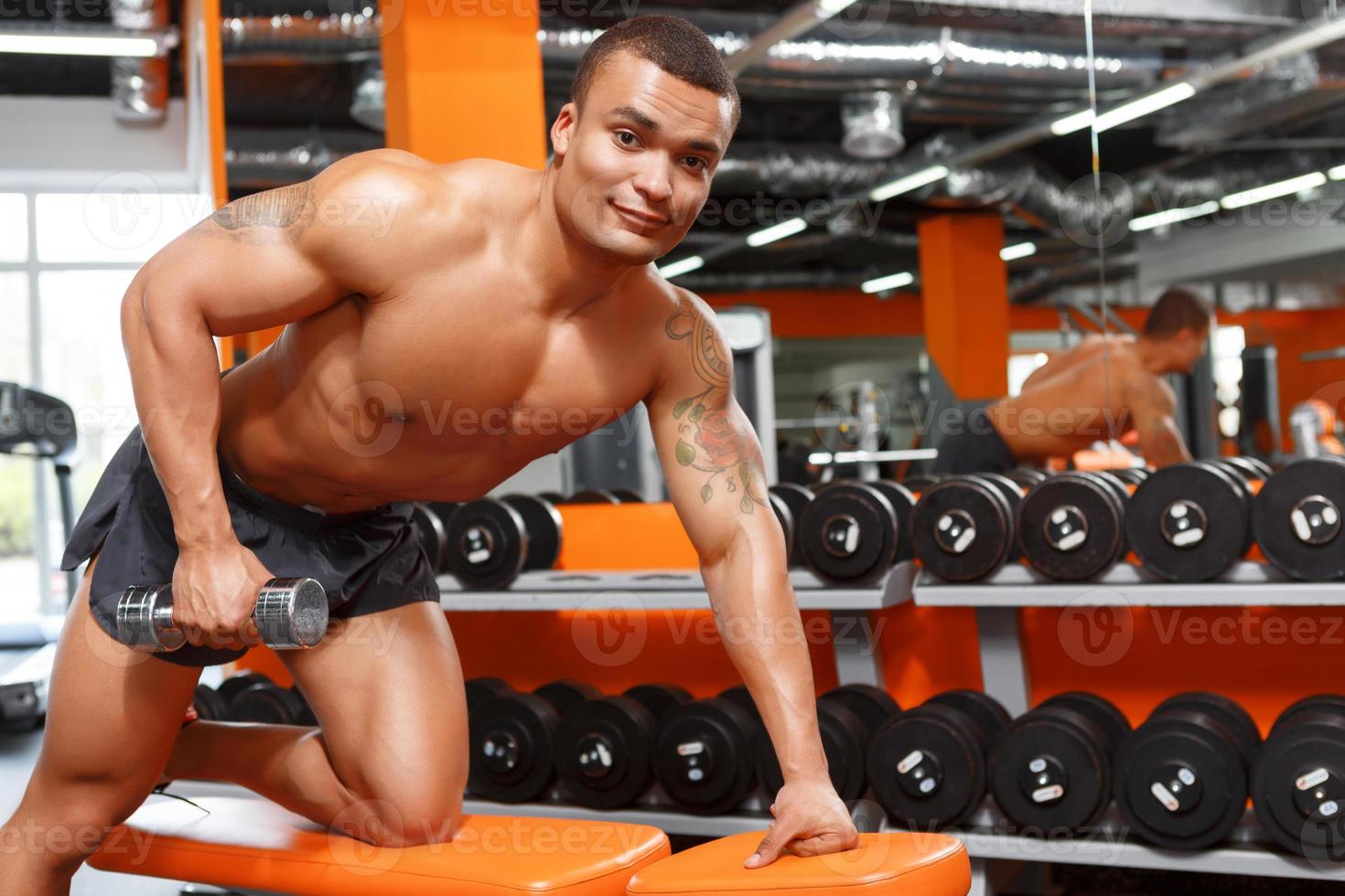 Muscular man doing exercises with dumbbells in gym photo