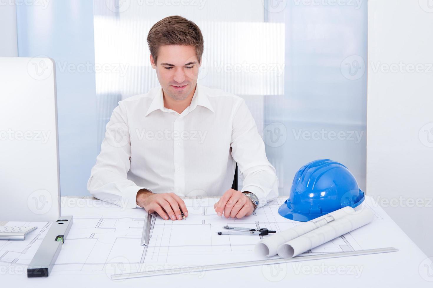 Young Architect Drawing Plan On Blueprint photo