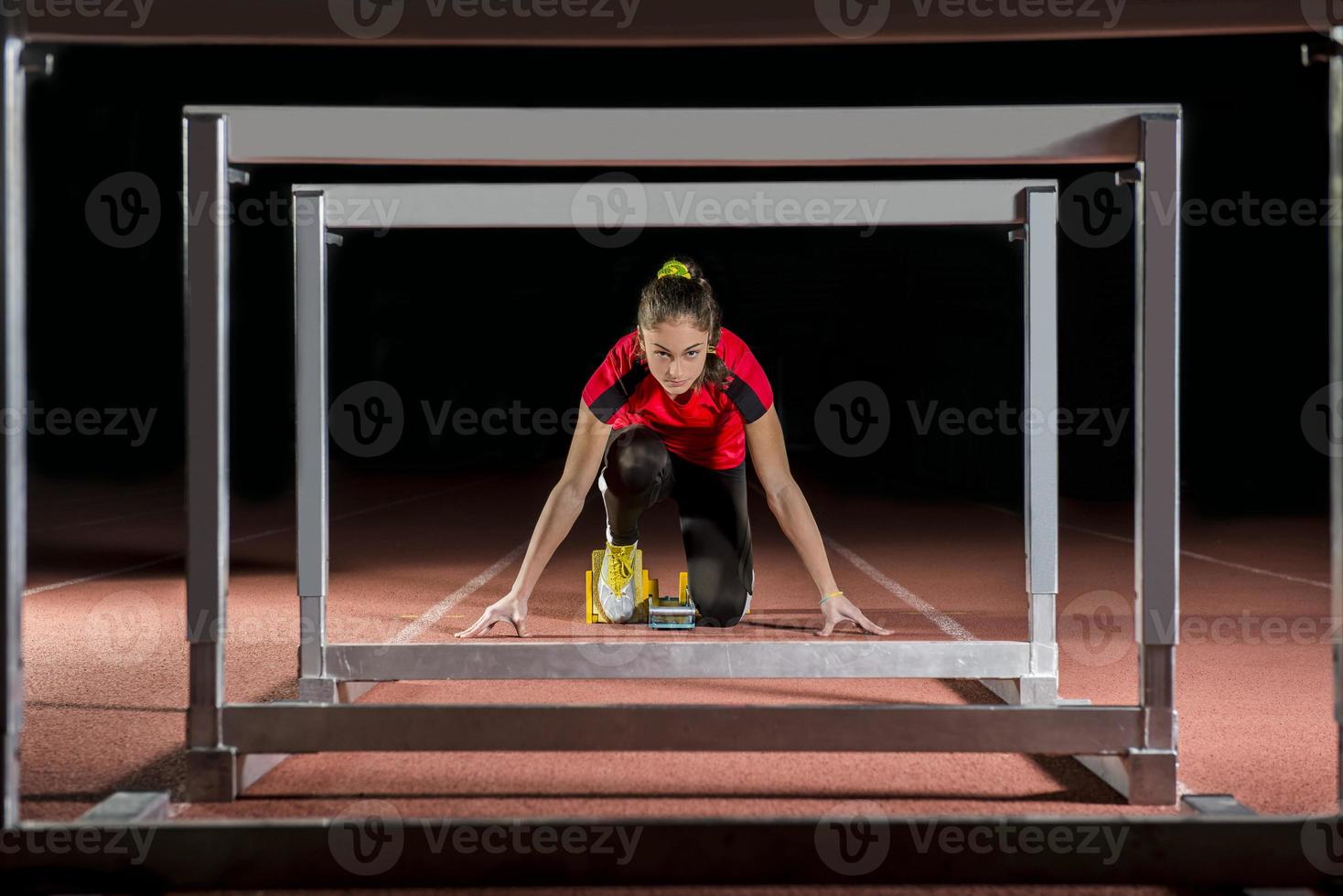 Athlete on the starting blocks with hurdles photo