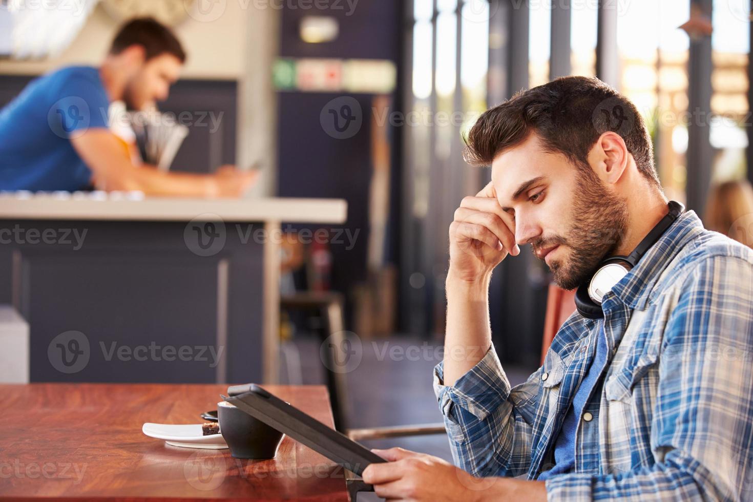 hombre usando tableta digital en una cafetería foto