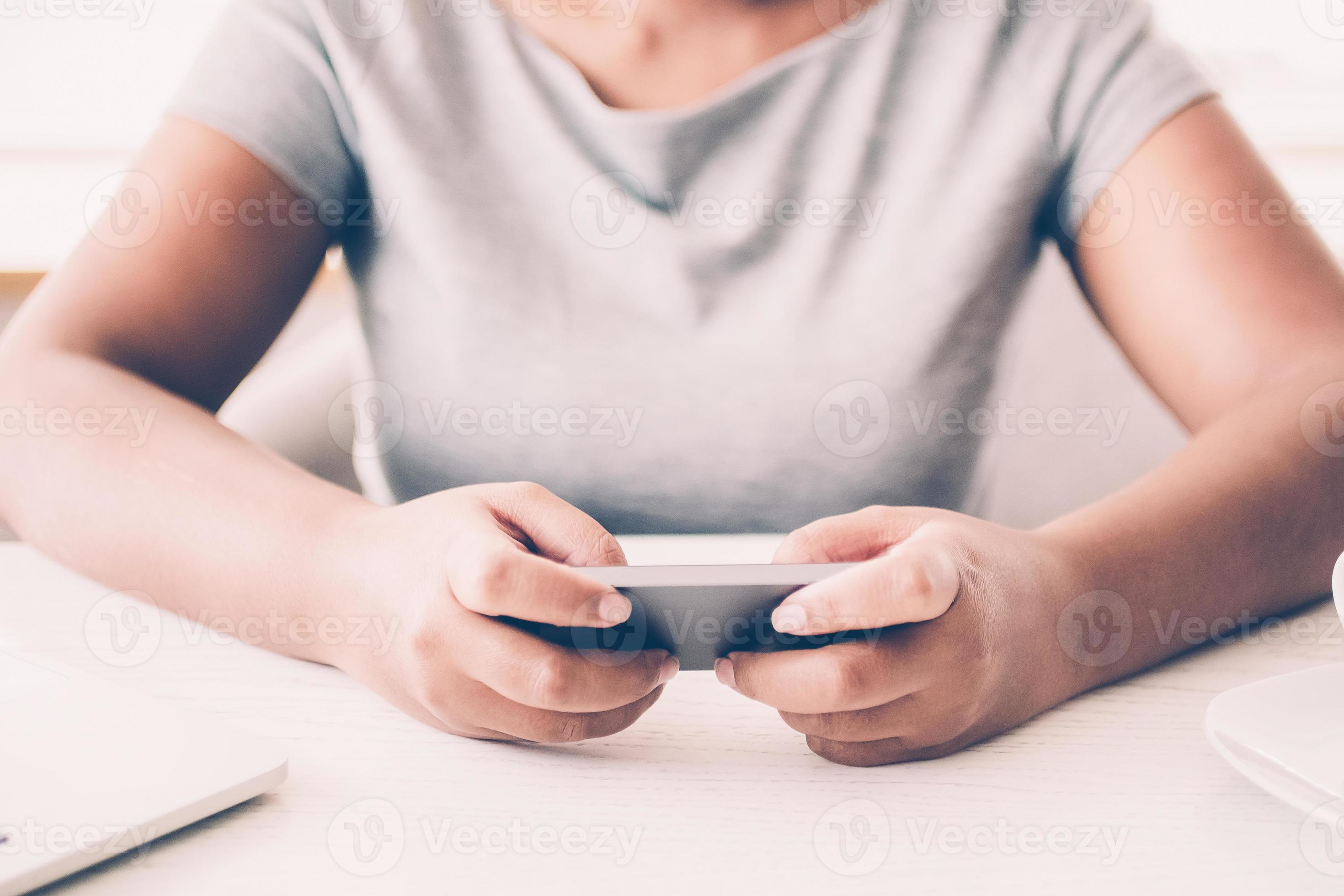 Close Up Of Woman Texting Message At Table Smiling Female Gamer Using Smartphone To Play Video Game Businesswoman Sitting At Desk With Laptop And Coffee Cup Technology Concept Stock Photo