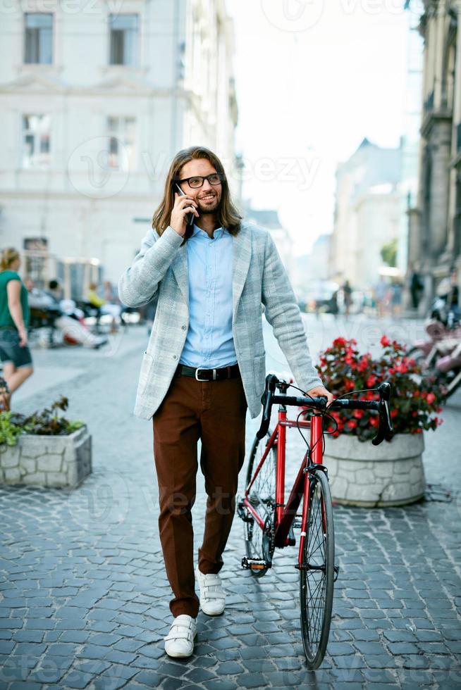 hombre en bicicleta de moda. Hombre con bicicleta y teléfono va a trabajar. foto