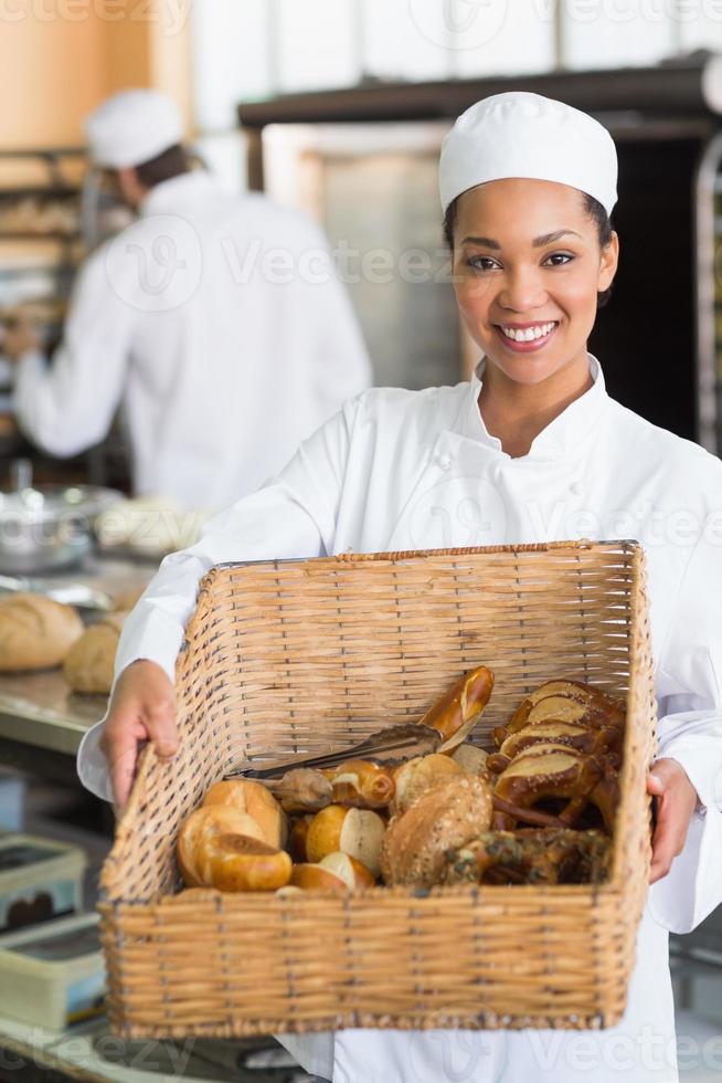 Pretty baker showing basket of bread photo