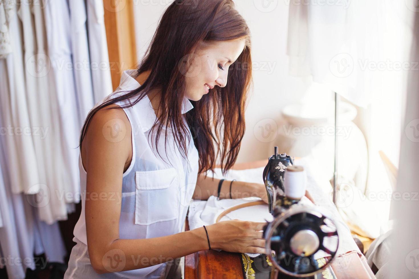 Smiley woman embroidering a white dress photo