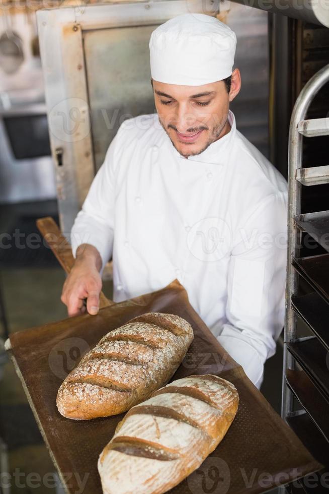 feliz panadero con bandeja de pan fresco foto